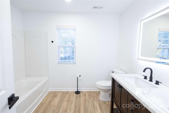 full bathroom featuring vanity, toilet, a healthy amount of sunlight, and hardwood / wood-style flooring