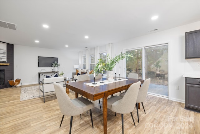 dining area featuring a large fireplace and light wood-type flooring