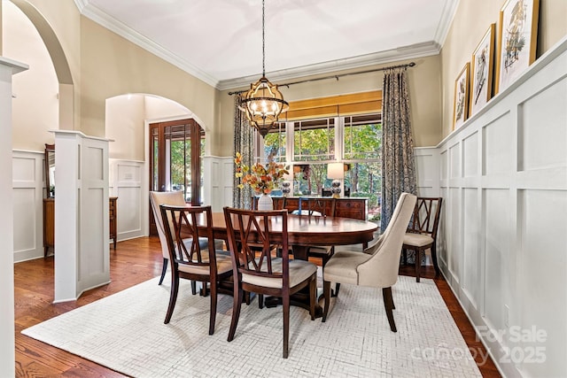 dining room with ornamental molding, a notable chandelier, and hardwood / wood-style floors