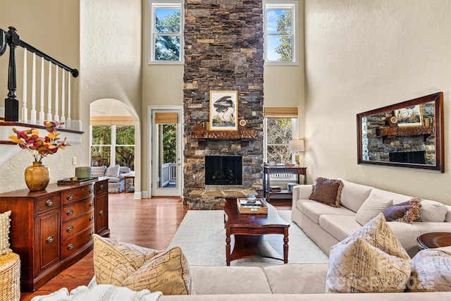 living room with plenty of natural light, a fireplace, light hardwood / wood-style floors, and a high ceiling