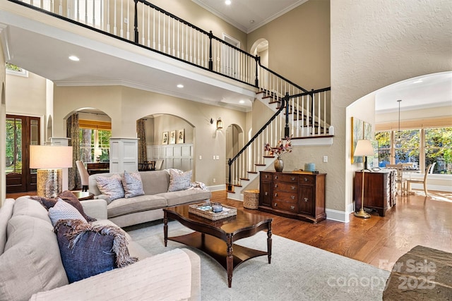 living room featuring wood-type flooring, ornamental molding, and a high ceiling