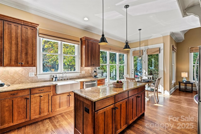 kitchen with sink, stainless steel dishwasher, decorative backsplash, decorative light fixtures, and light stone counters