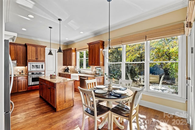 kitchen with light stone countertops, tasteful backsplash, decorative light fixtures, a kitchen island, and stainless steel appliances