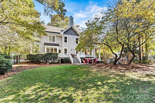 rear view of house featuring a wooden deck and a yard