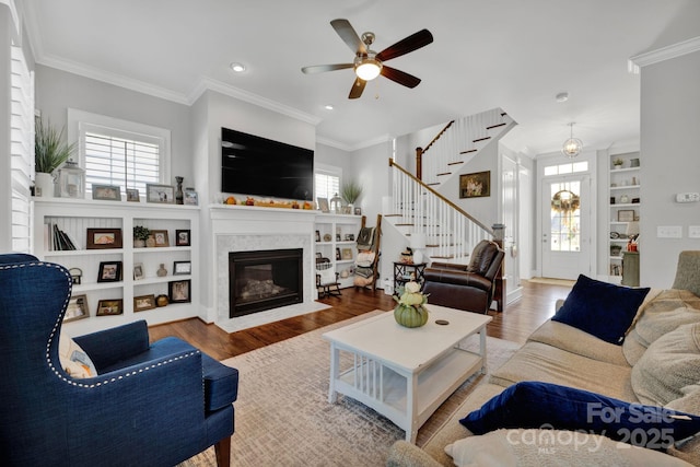 living room featuring ornamental molding, a healthy amount of sunlight, light hardwood / wood-style floors, and built in shelves