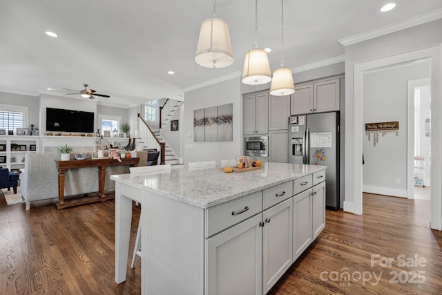 kitchen featuring stainless steel appliances, light stone countertops, a kitchen island, and gray cabinetry