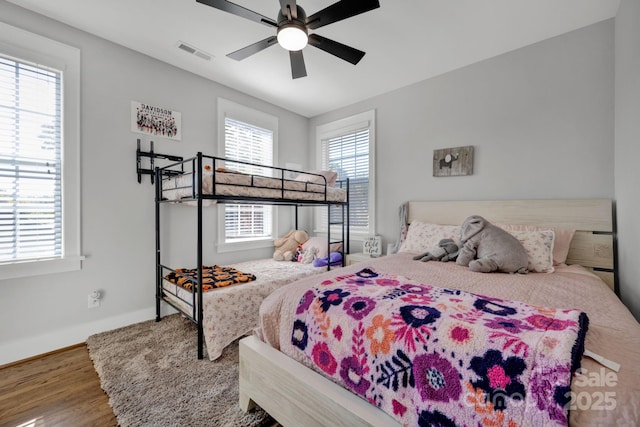 bedroom with multiple windows, hardwood / wood-style flooring, and ceiling fan