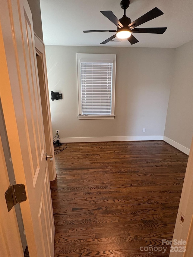 empty room with dark hardwood / wood-style flooring and ceiling fan