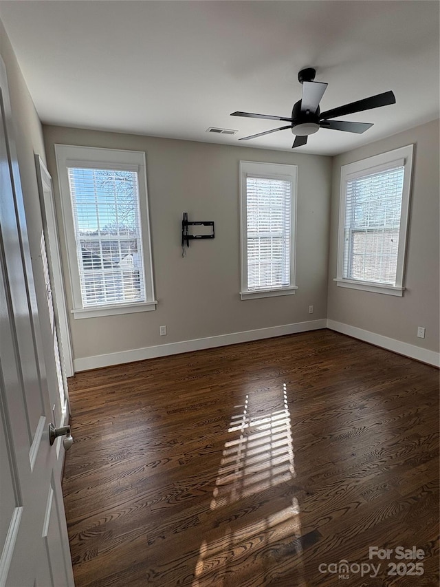 spare room featuring ceiling fan, a wealth of natural light, and dark hardwood / wood-style flooring