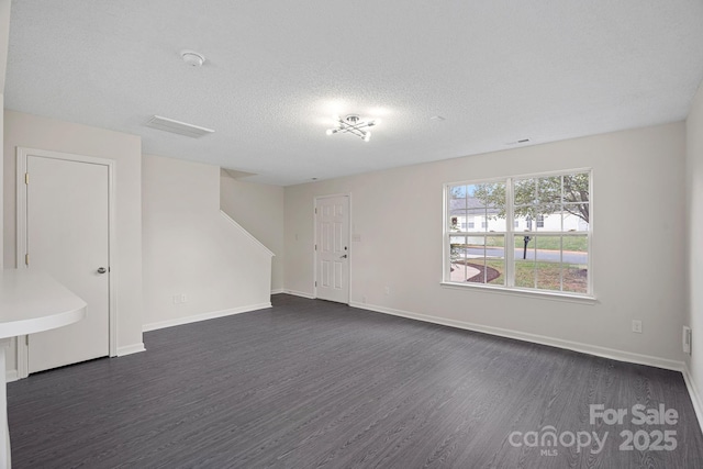 empty room with a textured ceiling and dark hardwood / wood-style flooring