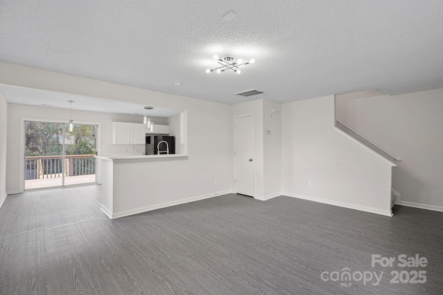 unfurnished living room featuring a textured ceiling and dark hardwood / wood-style flooring