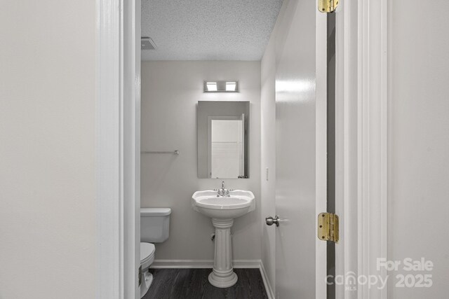 bathroom with a textured ceiling, toilet, and hardwood / wood-style floors