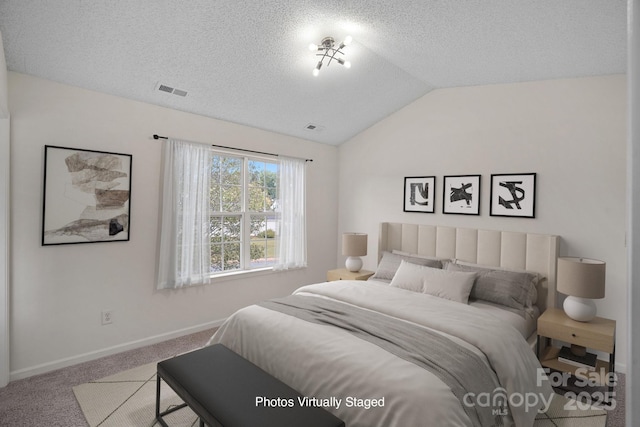 carpeted bedroom with vaulted ceiling and a textured ceiling