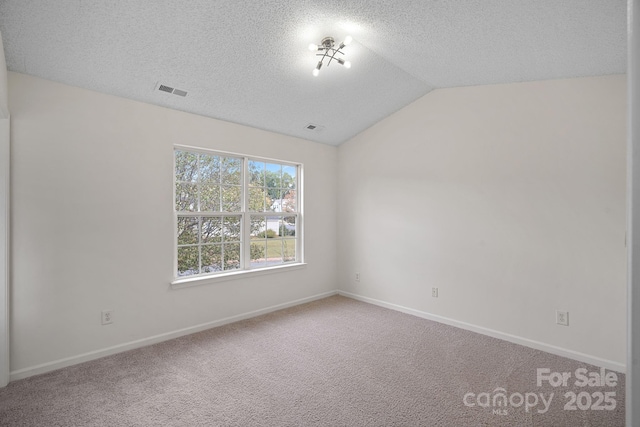 carpeted empty room with a textured ceiling and vaulted ceiling