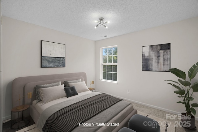 bedroom featuring an inviting chandelier, a textured ceiling, and carpet flooring