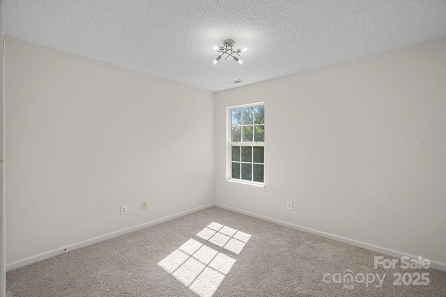 unfurnished room featuring carpet, a textured ceiling, and an inviting chandelier