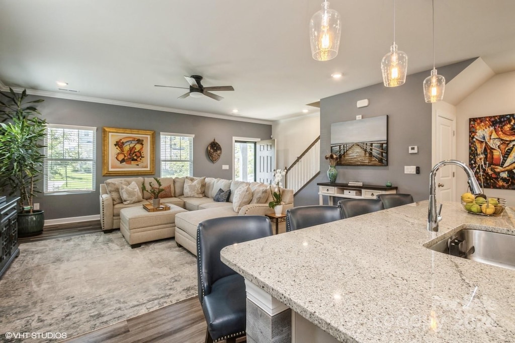 kitchen featuring wood-type flooring, light stone countertops, decorative light fixtures, and sink