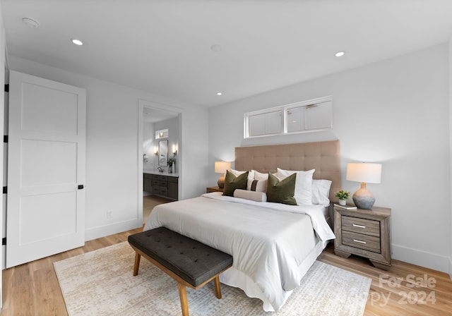 bedroom with ensuite bathroom and light hardwood / wood-style floors