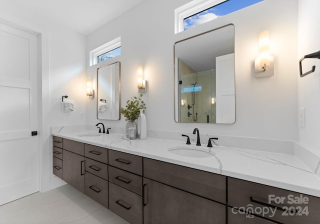 bathroom with tile patterned flooring, vanity, a healthy amount of sunlight, and walk in shower