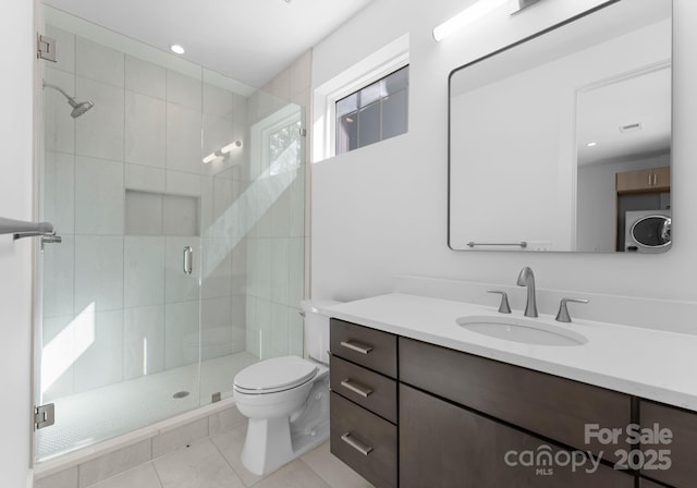 bathroom with walk in shower, tile patterned floors, toilet, vanity, and washer / clothes dryer