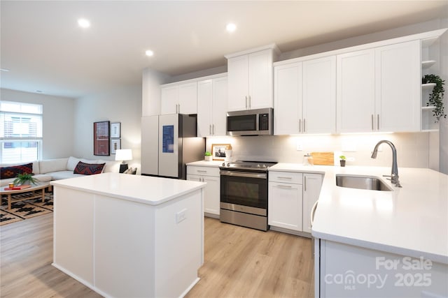 kitchen featuring sink, white cabinetry, a center island, stainless steel appliances, and light hardwood / wood-style floors