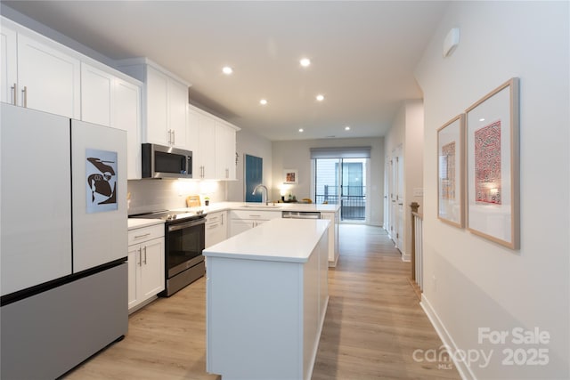 kitchen with white cabinetry, appliances with stainless steel finishes, kitchen peninsula, and sink