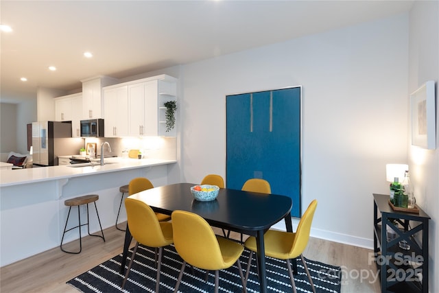 dining space with sink and light hardwood / wood-style floors