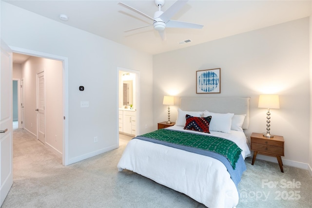 bedroom featuring ensuite bath, light colored carpet, and ceiling fan