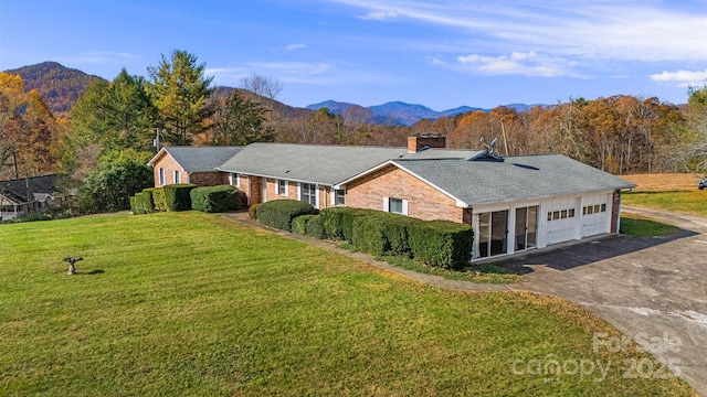 view of front of house with a garage, a mountain view, and a front yard