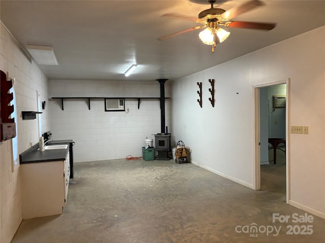 basement featuring a wood stove and ceiling fan