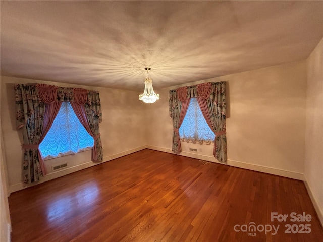 spare room featuring hardwood / wood-style floors and an inviting chandelier