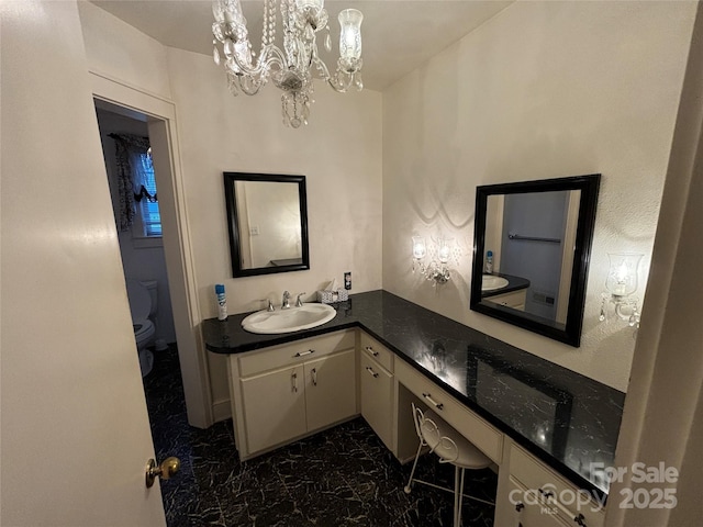 bathroom featuring a notable chandelier, vanity, and toilet