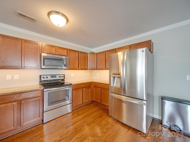 kitchen featuring light hardwood / wood-style floors, stainless steel appliances, and crown molding