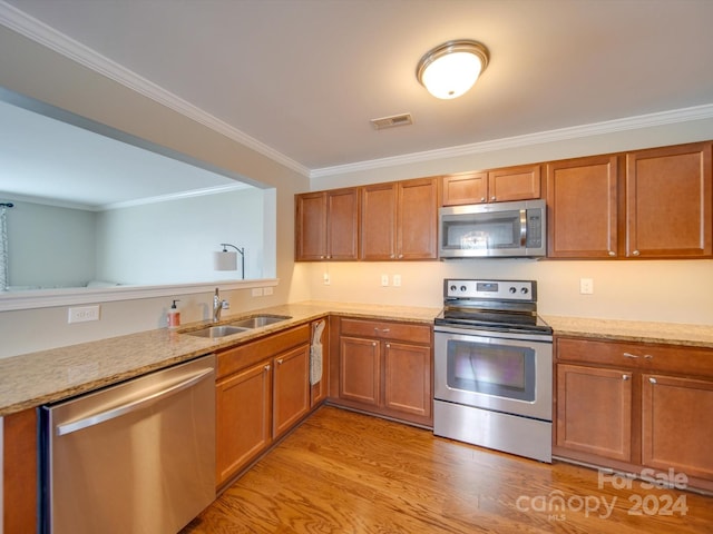 kitchen with light hardwood / wood-style flooring, stainless steel appliances, sink, and crown molding