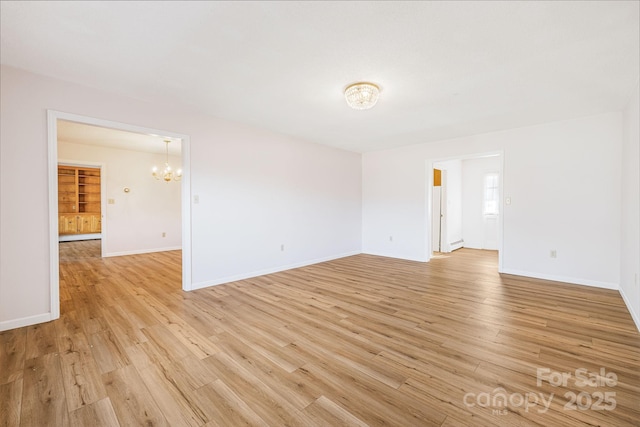 empty room featuring an inviting chandelier and light hardwood / wood-style floors