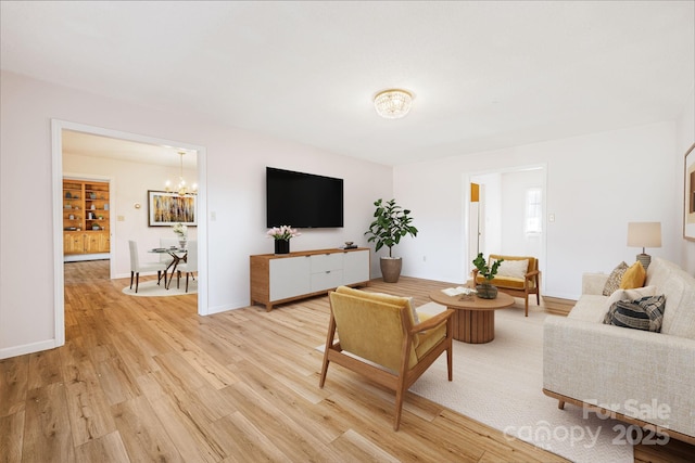 living room with an inviting chandelier and light hardwood / wood-style flooring