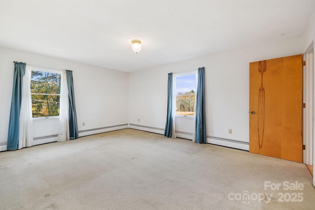 spare room with baseboard heating and light colored carpet