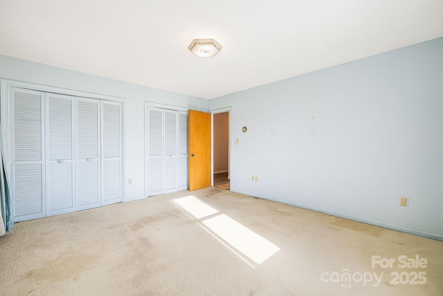 unfurnished bedroom featuring carpet floors and two closets