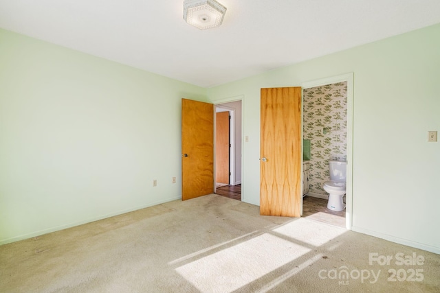 unfurnished bedroom featuring light colored carpet and ensuite bathroom