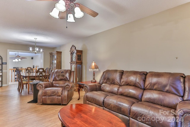 living room featuring light hardwood / wood-style floors, a textured ceiling, and ceiling fan with notable chandelier