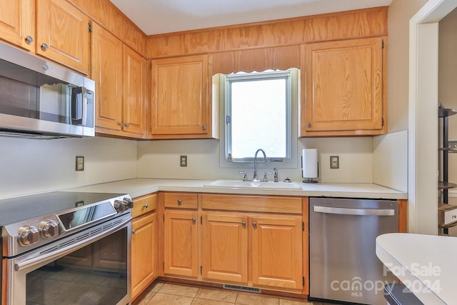 kitchen featuring a textured ceiling, stainless steel appliances, sink, and light tile patterned floors