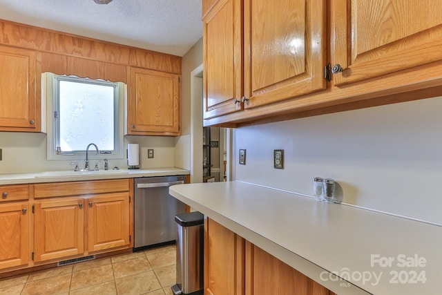 kitchen with a textured ceiling, stainless steel dishwasher, sink, and light tile patterned floors