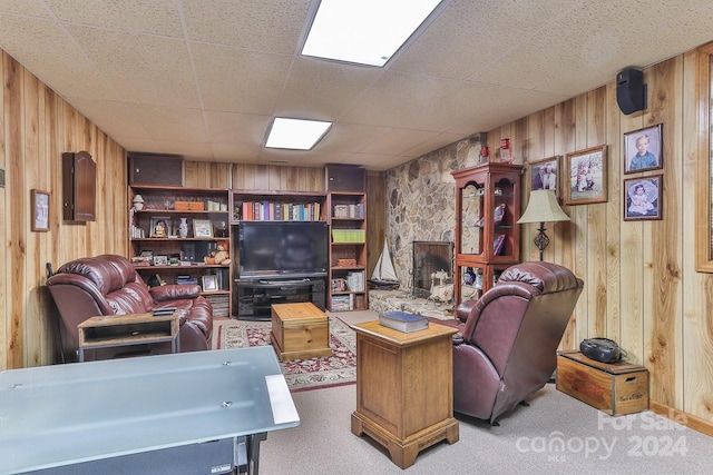 carpeted living room featuring wood walls and a stone fireplace