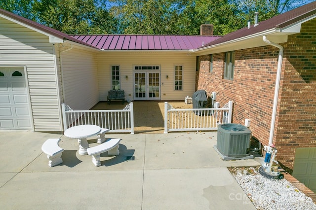 exterior space featuring french doors, a patio area, cooling unit, and a garage