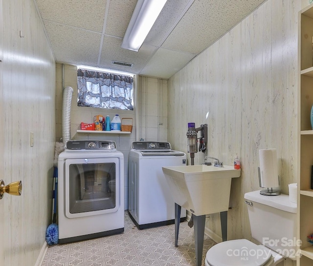 washroom featuring wooden walls and separate washer and dryer