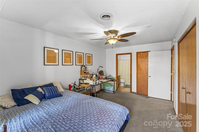 carpeted bedroom featuring ceiling fan, a textured ceiling, ensuite bathroom, and a closet