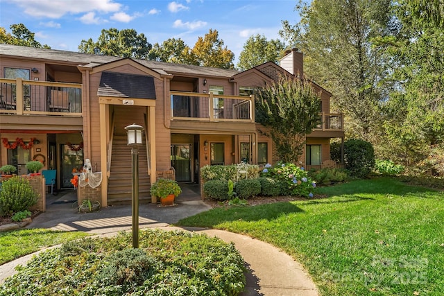 townhome / multi-family property featuring a balcony and a front yard