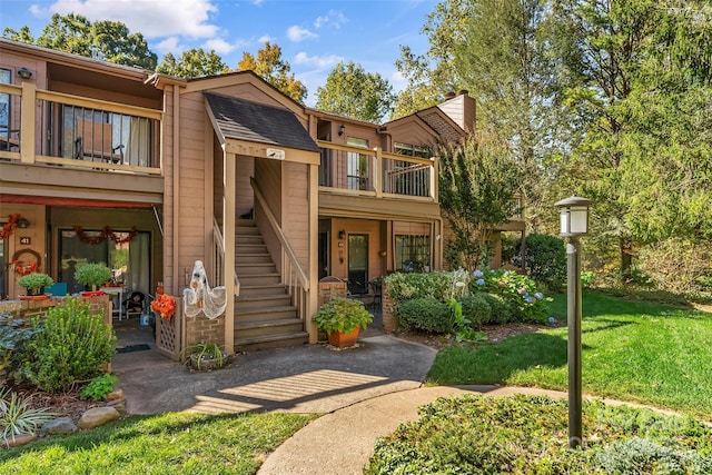 multi unit property featuring a balcony and a front lawn