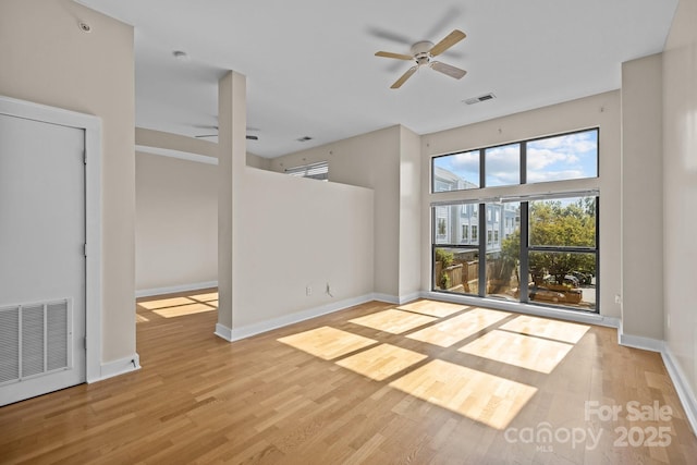 unfurnished living room featuring a towering ceiling, ceiling fan, and light wood-type flooring