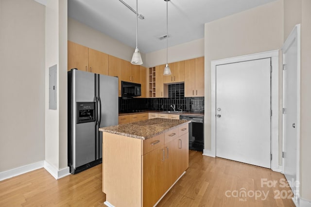 kitchen featuring hanging light fixtures, a center island, black appliances, dark stone counters, and light brown cabinets